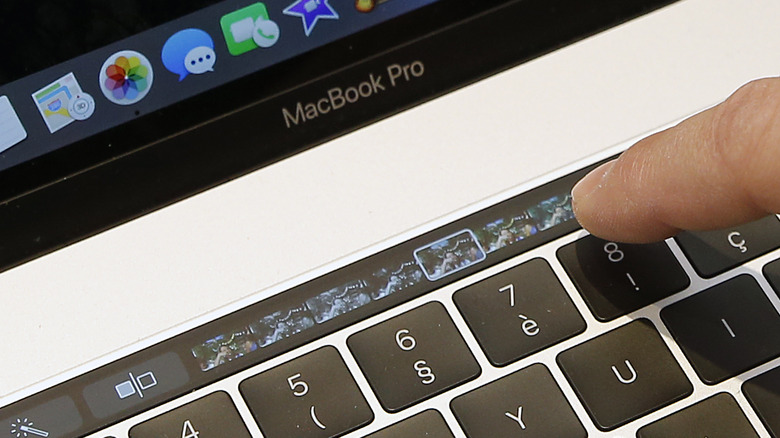 Человек взаимодействует с MacBook Pro Touch Bar.