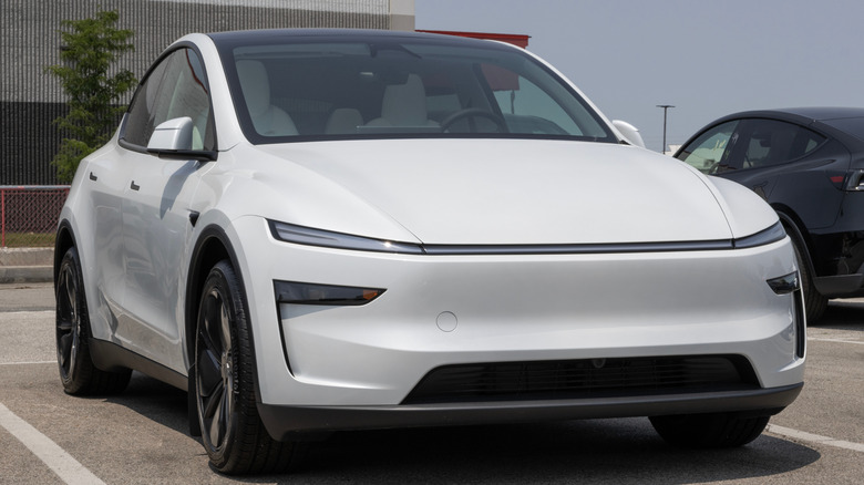 Белая модель Tesla Y на парковке.