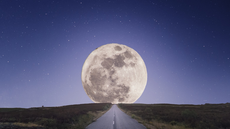 Визуальное изображение луны в небе перед дорогой.