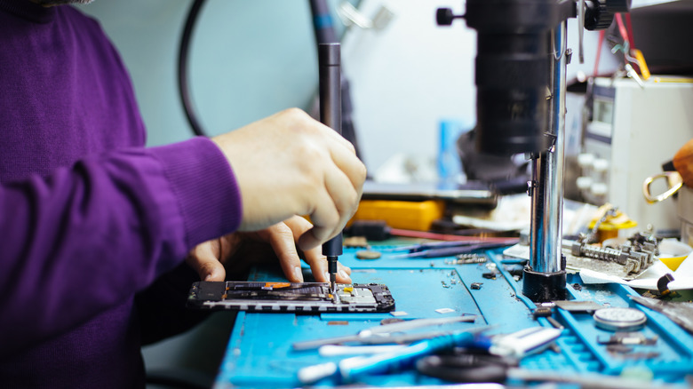 Техник разборка смартфона с помощью отвертки.