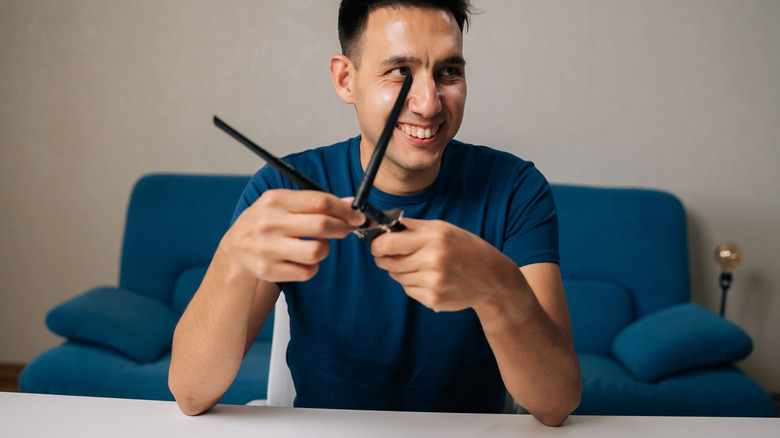 Портрет улыбающегося техника мужского пола собирает Wi-Fi модуль путем подключения антенн