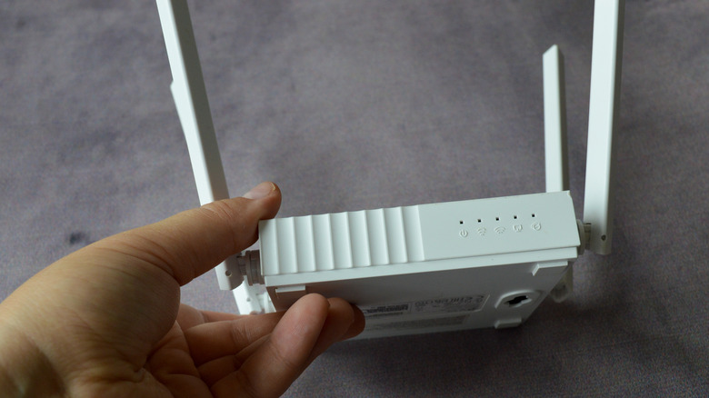 Роутер Wi-Fi с четырьмя антеннами, удерживаемыми в руке.