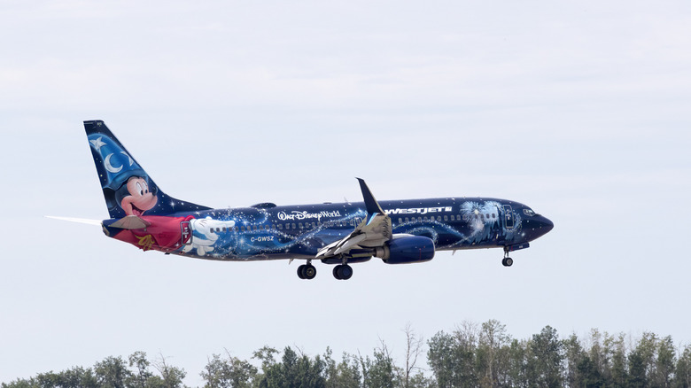 Пассажирский самолет Westjet с ливреей Диснея, летающей на очень низкой высоте, видом на сторону