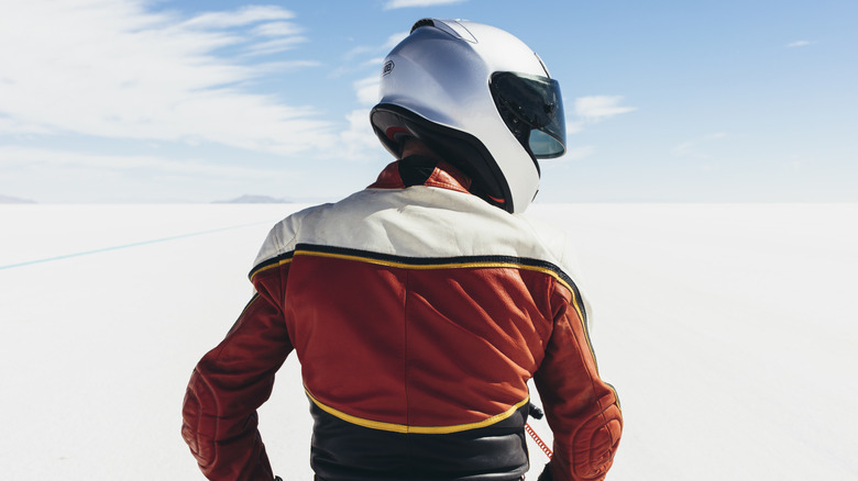 Мотоциклетный гонщик в шлеме и куртке, просмотренном сзади