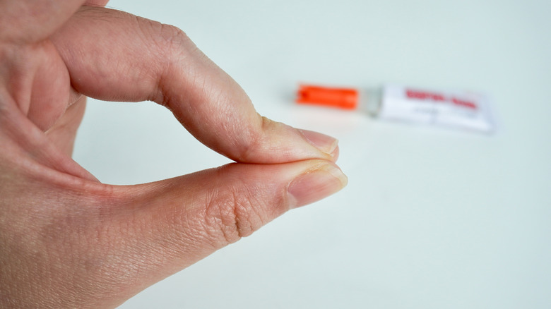 Пальцы застряли вместе с трубкой клей на заднем плане