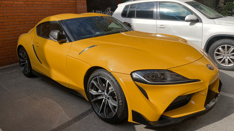 Желтый спортивный автомобиль Toyota Supra GR V (A90, A91) MK 5 на парковке на улице.