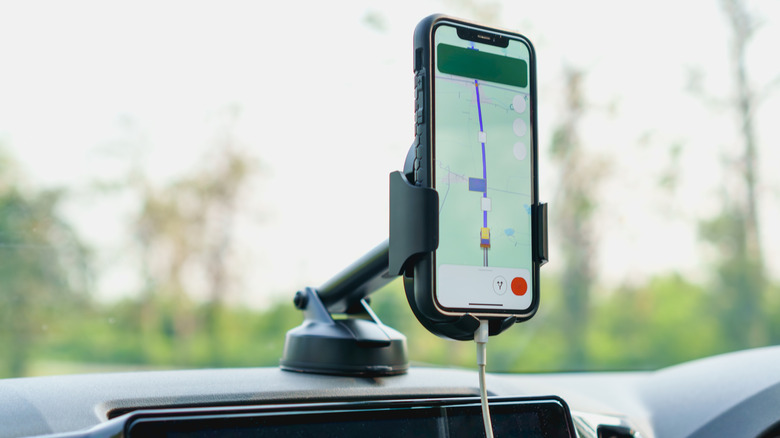 Телефон установился на приборной панели автомобиля, показывающий направления GPS.