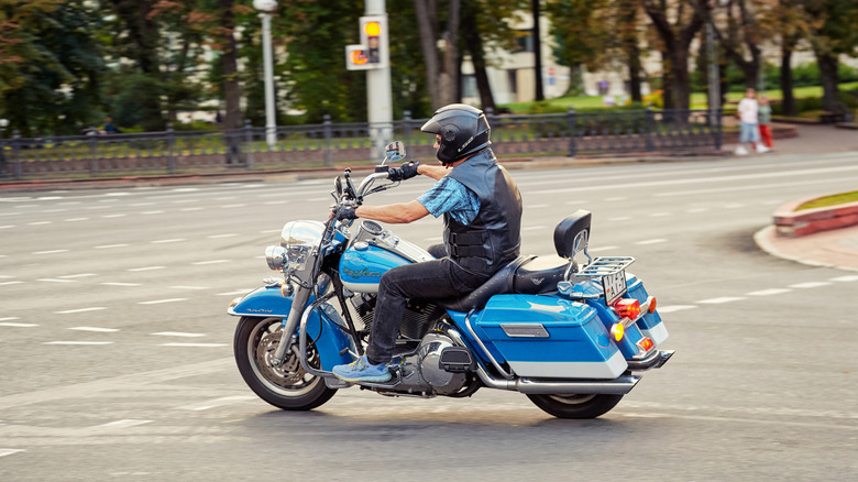 Байкер ездит на Blue Harley Davidson Road King, поворачиваясь на дорогу