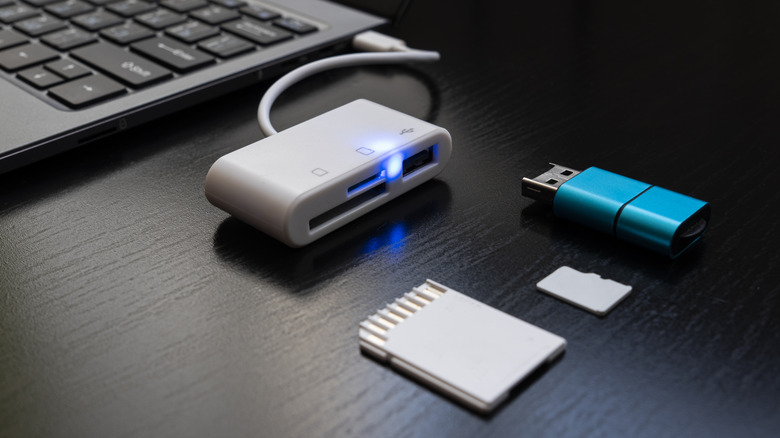флешка и карты памяти перед USB-хабом, подключенным к ноутбуку