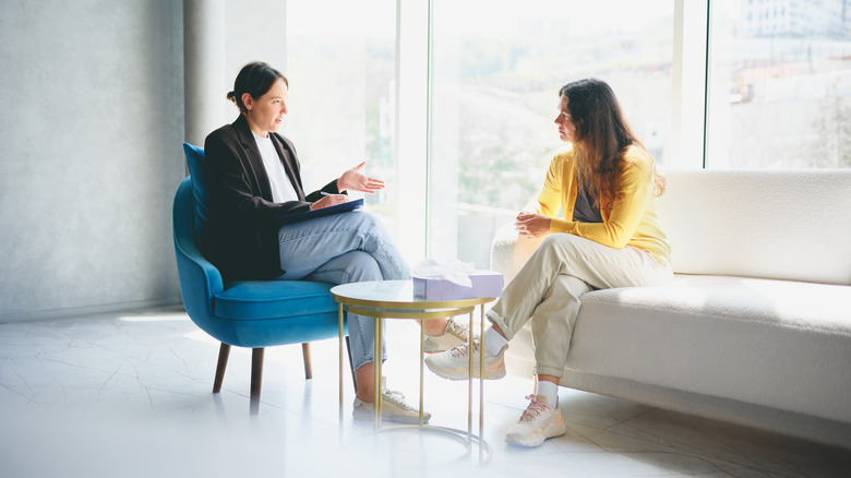 Женщина разговаривает с женщиной-терапевтом у яркого окна