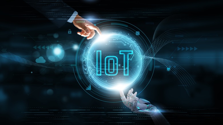 Человек и робот касаются голограммы Интернета вещей.