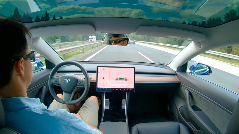 Мужчина за рулем беспилотной Tesla на шоссе