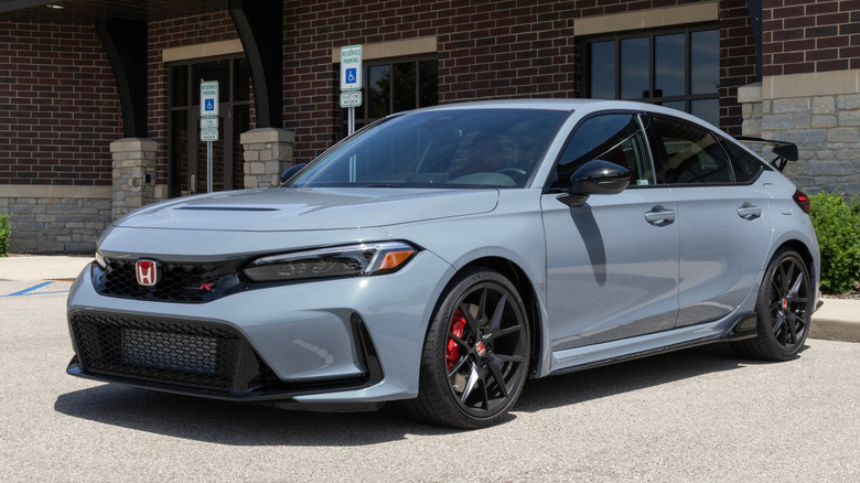 Нардо-синяя Honda Civic Type R 2024 года выпуска, припаркованная возле здания из красного кирпича.