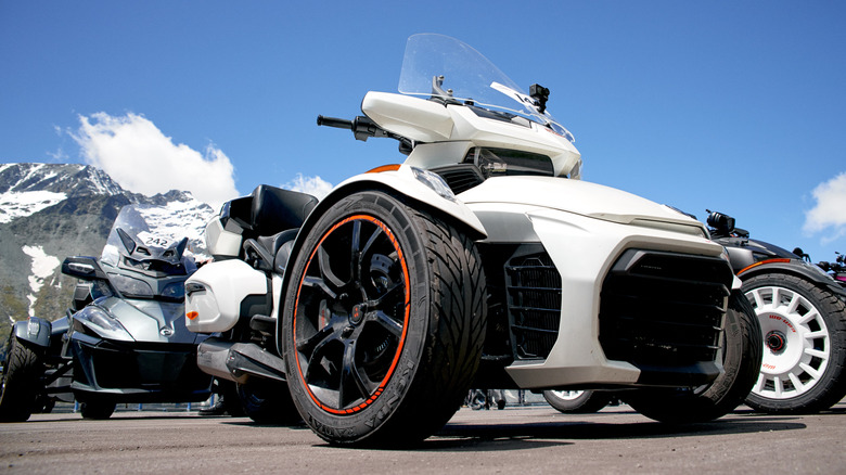 Белый Can Am Spyder рядом с другими трехколесными автомобилями Can Am в Австрии, вид спереди на 3/4, крупный план под низким углом