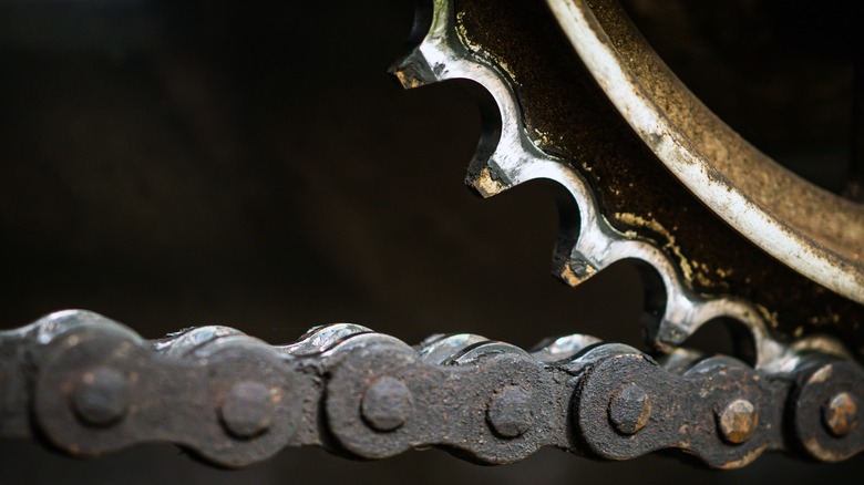 Грязная мотоциклетная цепь и изношенная звездочка