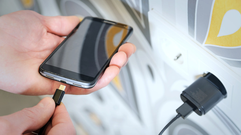 Человек заряжает смартфон.