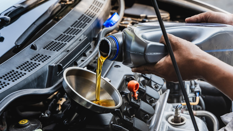 Владелец автомобиля заливает новое масло