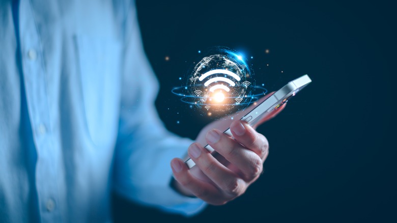 Человек, держащий в руках телефон с плавающим изображением WIFI в пузыре