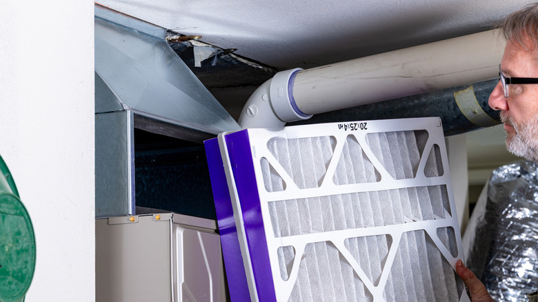 Человек меняет фильтр печи.