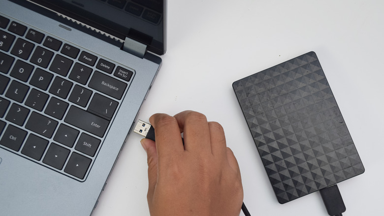 Человек, подключающий внешний жесткий диск к ноутбуку.