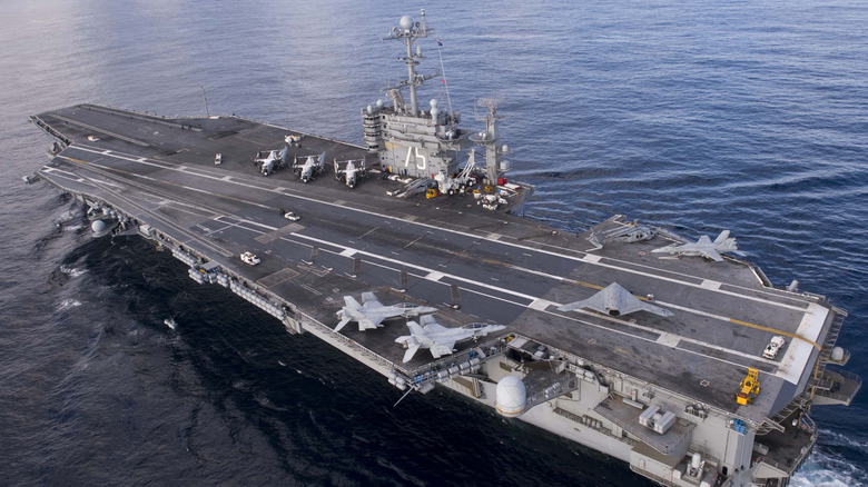 Авианосец в спокойной воде с несколькими самолетами на палубе