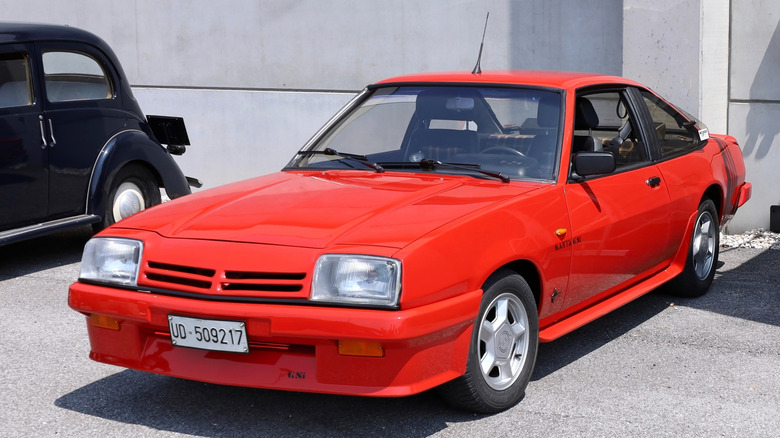 Красный Opel Manta B припаркован перед зданием