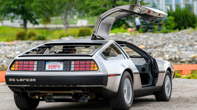 Вид сзади на DeLorean DMC-12, припаркованный с открытой правой дверью.