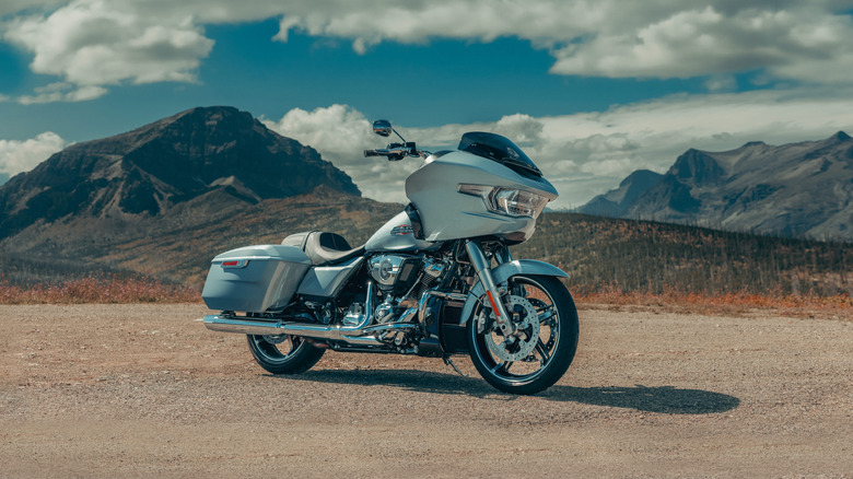 Серебристый Harley-Davidson Road Glide, вид спереди в 3/4, на заднем плане горы