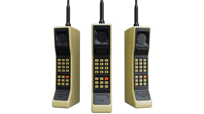 Три телефона Motorola DynaTAC, расположенные рядом, цифровыми клавиатурами, обращенными к камере.
