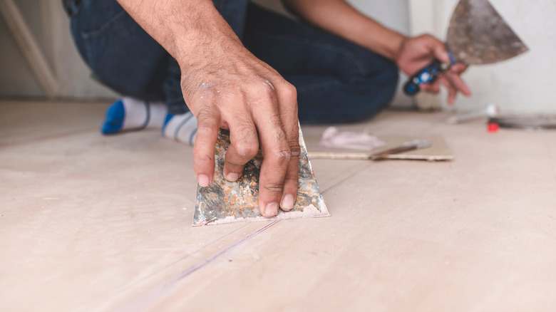 Мужчина заполняет дыры на полу