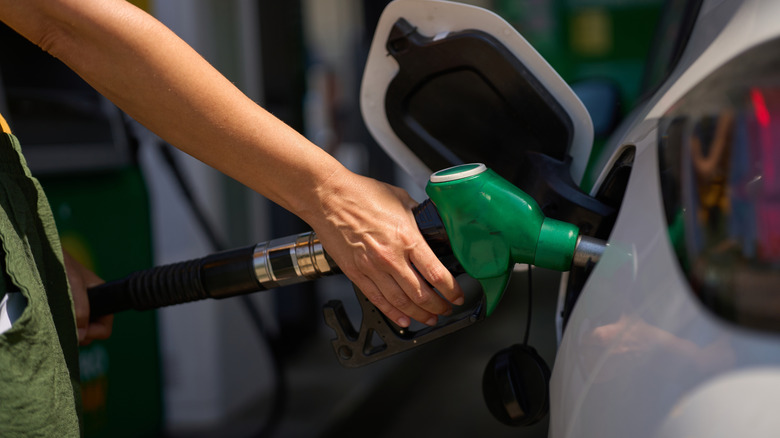 Водитель заправляет машину дизельным бензонасосом