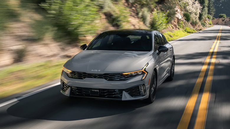 Снимок передней части серого Kia K5 2026 года за рулем.