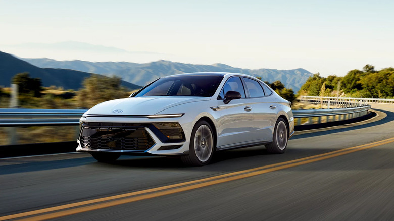 Фронтальный снимок белого Hyundai Sonata 2026 года выпуска в три четверти за рулем.