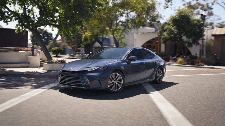 Вид сбоку серой Toyota Camry 2026 года за рулем.