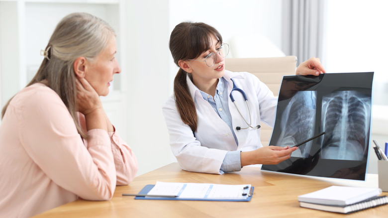 Врач показывает пациенту рентген грудной клетки на офисном компьютере