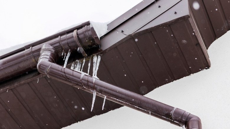 Ледяная плотина в желобе дома на крыше