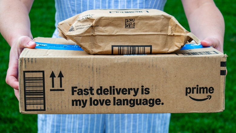 Человек, держащий две посылки Amazon