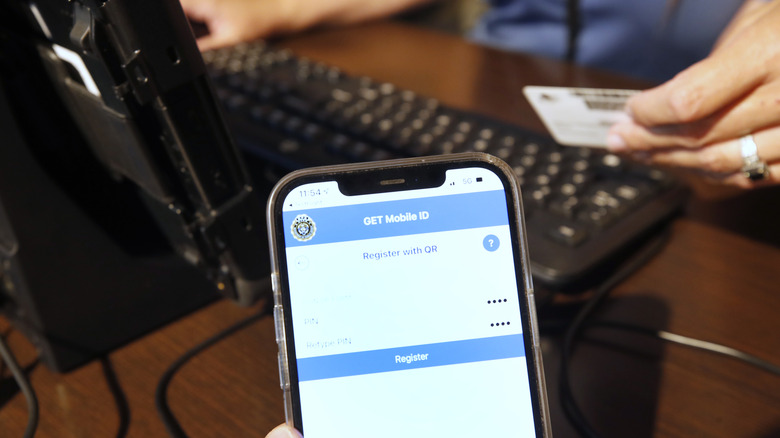 Сотрудник Департамента транспортных средств штата Юта помогает мужчине преобразовать его физические водительские права в официальные цифровые версии.