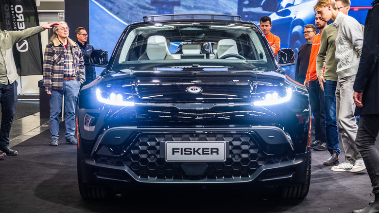 Вид спереди припаркованного черного внедорожника Fisker Ocean в окружении людей.