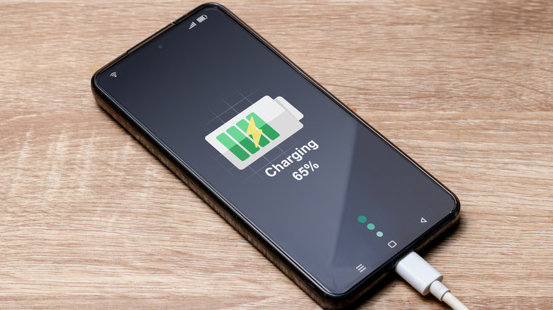 Смартфон на зарядке на столе.