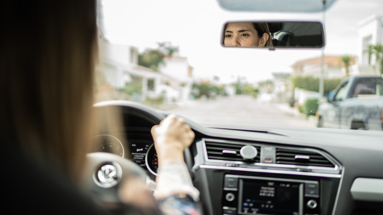 Лицо водителя отражается в зеркале заднего вида.