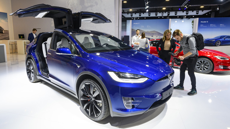 Синяя Tesla Model X с открытыми дверями на автосалоне