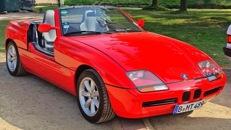 Вид спереди на красный кабриолет BMW Z1 на стоянке с травой и деревьями позади