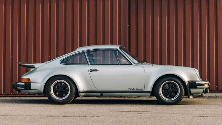 Вид сбоку на 911 Turbo на асфальте с транспортным контейнером на заднем плане