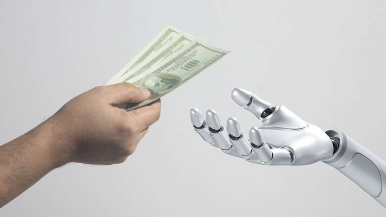 Человеческая рука передает банкноты руке робота