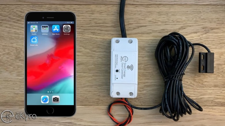 Комплект интеллектуального контроллера гаражных ворот eKyro показан со смартфоном.