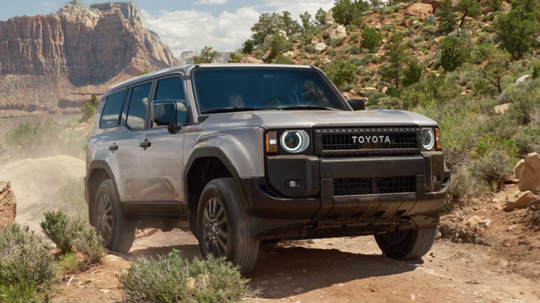 Передняя часть 3: вид синей Toyota Land Cruiser, едущей по грунтовой дороге