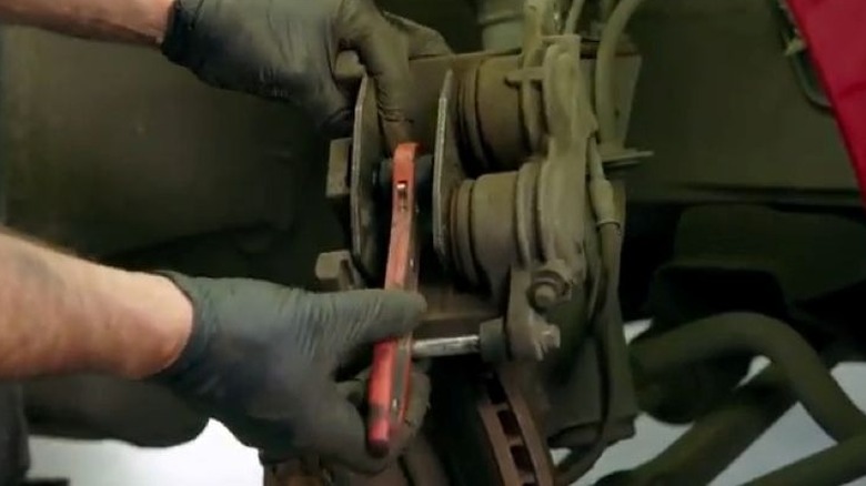 Человек, использующий расширитель колодок на тормозном суппорте