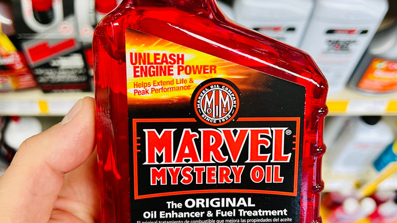 Рука держит бутылку масла Marvel Mystery Oil.