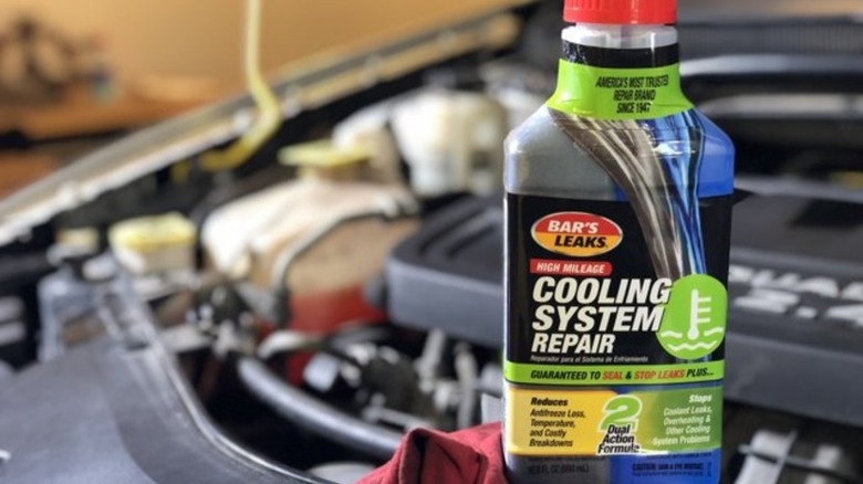 Банка с жидкостью для ремонта системы охлаждения на двигателе.